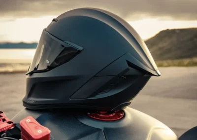 Ruroc EOX motorcycle helmet in a matte black finish, showing its aerodynamic profile and Quad-Matrix carbon fiber shell.