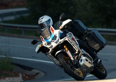 A rider wearing the Shoei GT-Air 3 helmet while riding a sport-touring motorcycle on a winding road.