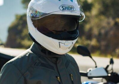 A rider wearing the Shoei GT-Air 3 helmet while riding a sport-touring motorcycle on a winding road.