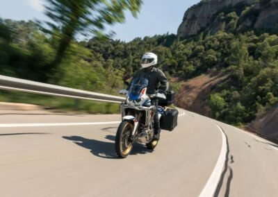 A rider wearing the Shoei GT-Air 3 helmet while riding a sport-touring motorcycle on a winding road.