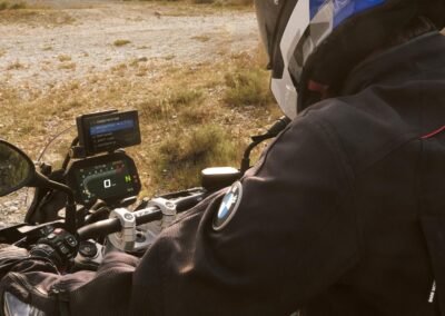 A rider wearing the BMW GS Rallye Carbon helmet while riding a BMW R 1300 GS motorcycle on a dirt road.