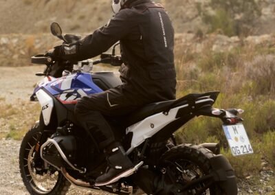 A rider wearing the BMW GS Rallye Carbon helmet while riding a BMW R 1300 GS motorcycle on a dirt road.
