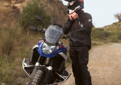 A rider wearing the BMW GS Rallye Carbon helmet while riding a BMW R 1300 GS motorcycle on a dirt road.