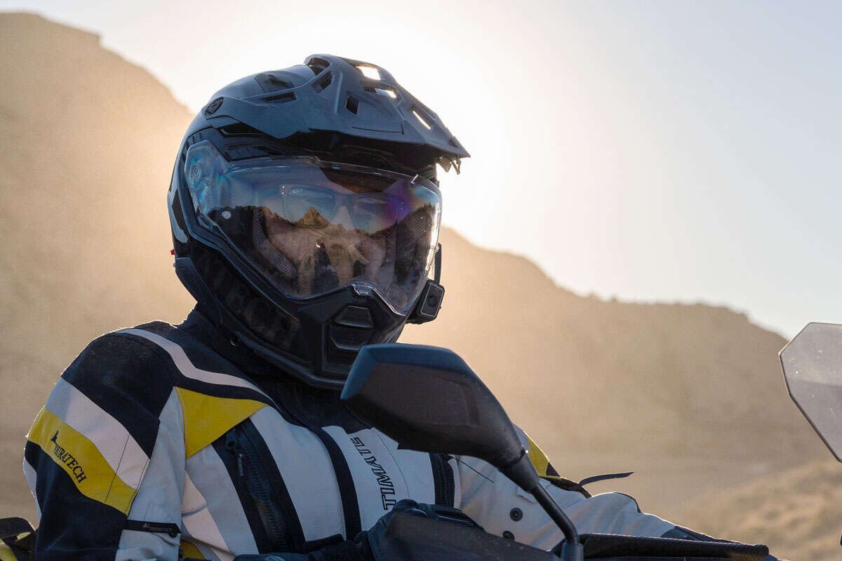 The Touratech Aventuro Carbon Pro helmet in matte black, shown in its full adventure configuration with peak and visor.