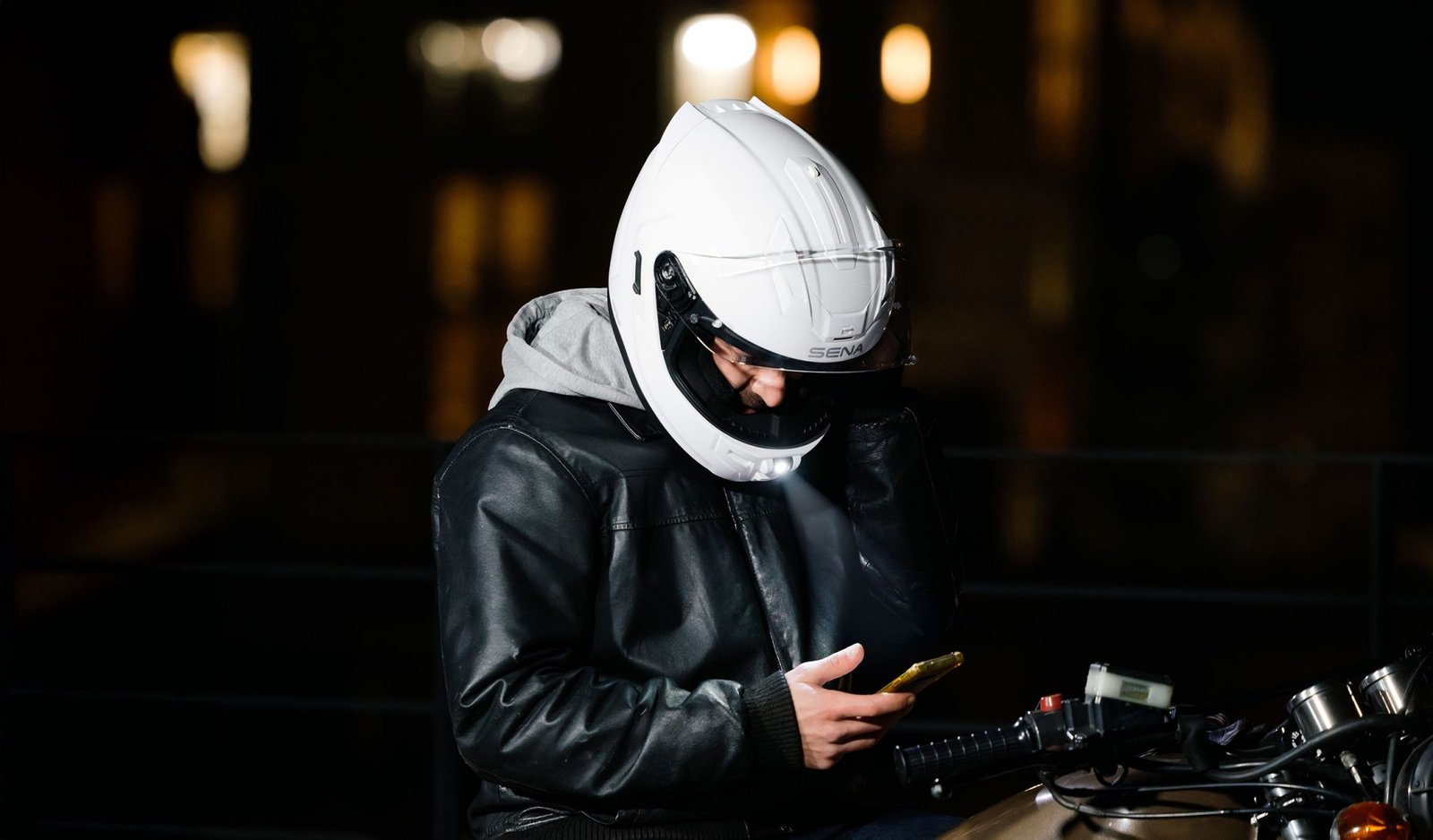 Rider on a sport-touring motorcycle wearing the ECE 22.06 certified Sena Phantom smart helmet