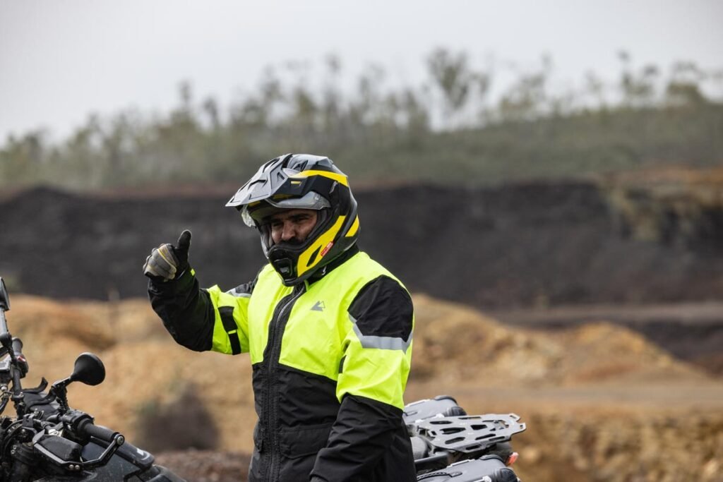 The two-piece black and yellow Touratech Storm Rain Suit displayed on a mannequin over a full riding suit.
