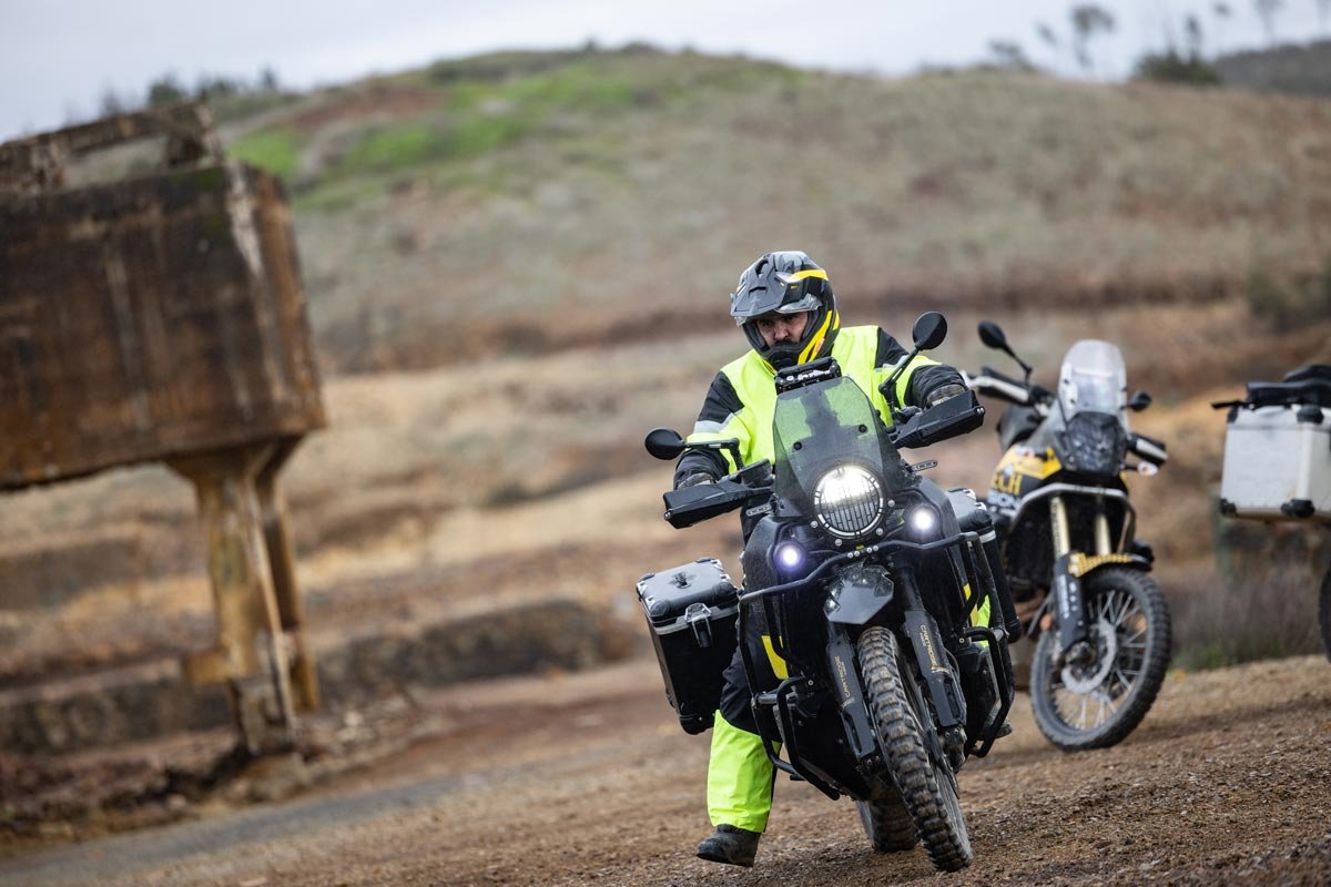 202303_Touratech-Regenanzug-Storm-2 Action shot of a rider on a BMW GS motorcycle wearing the Touratech Storm Rain Suit in heavy rain.