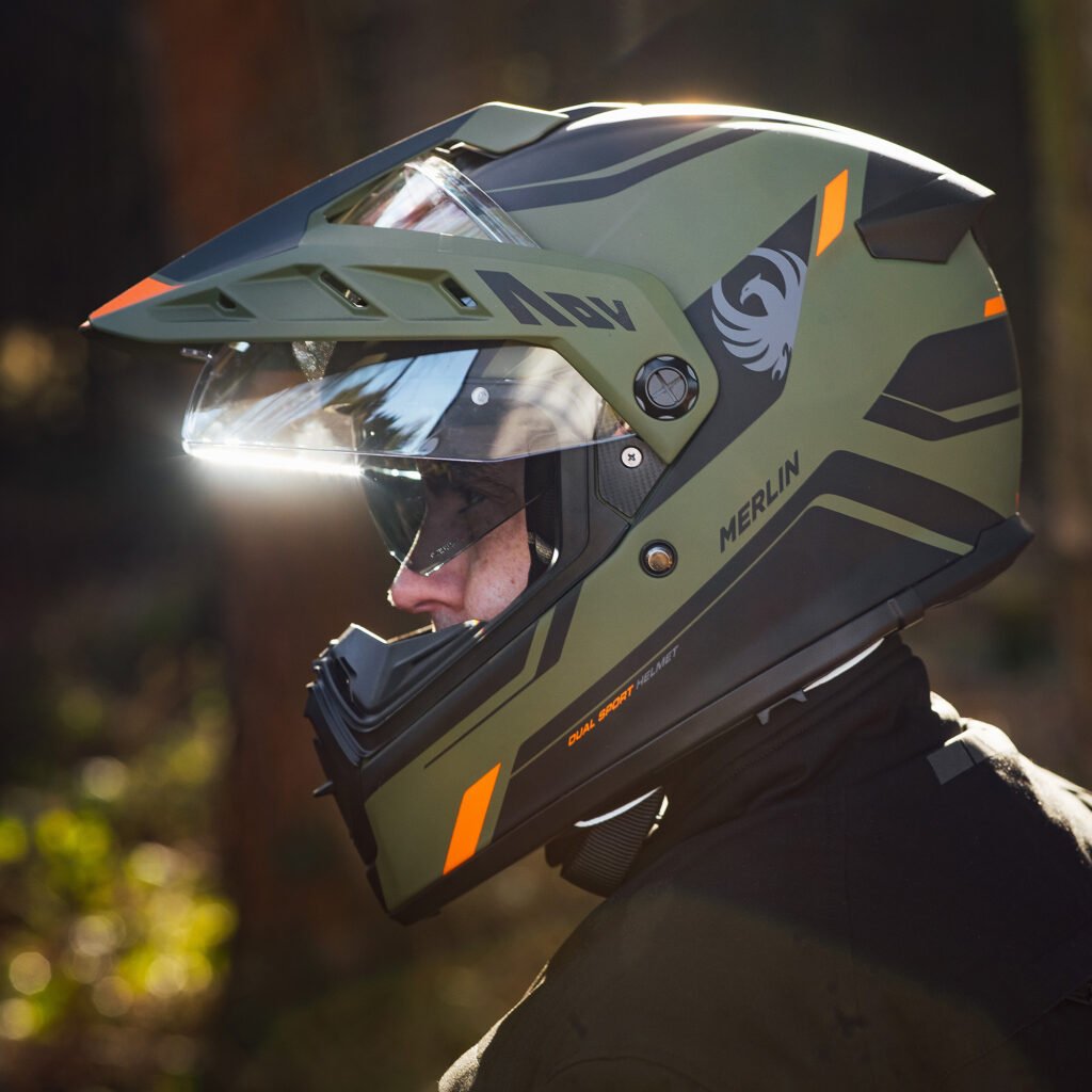 A rider wearing the Merlin Torres helmet on an adventure motorcycle, demonstrating the helmet's scale and on-bike profile.