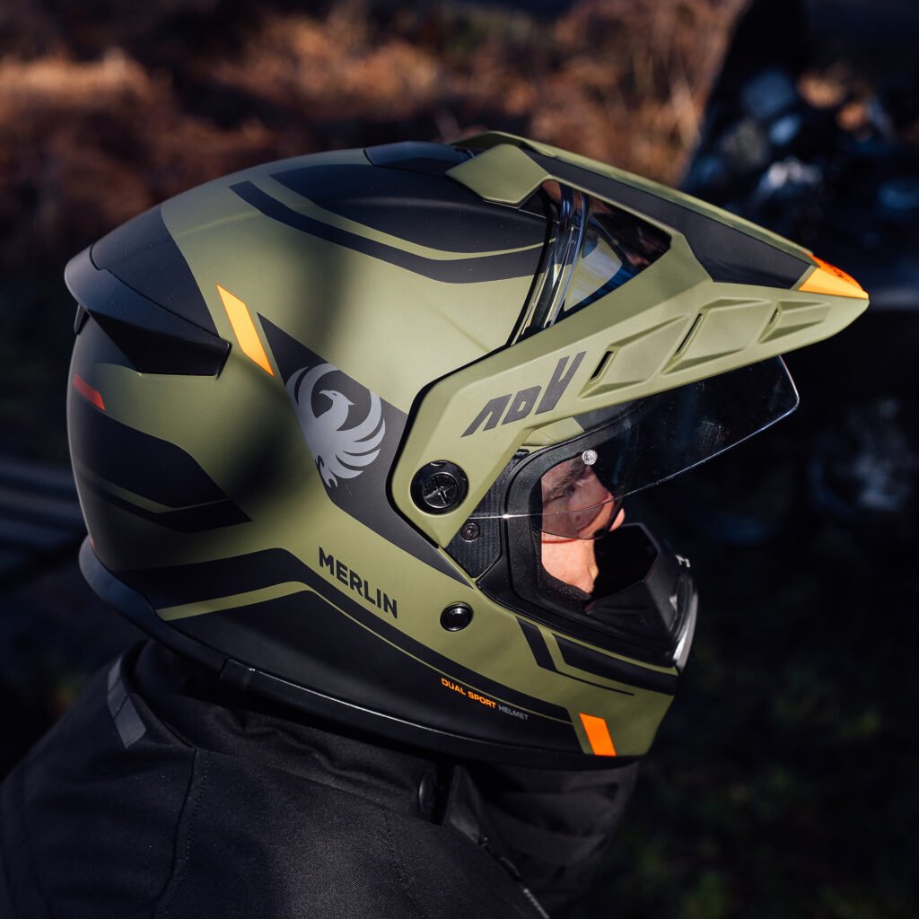 A rider wearing the Merlin Torres helmet on an adventure motorcycle, demonstrating the helmet's scale and on-bike profile.