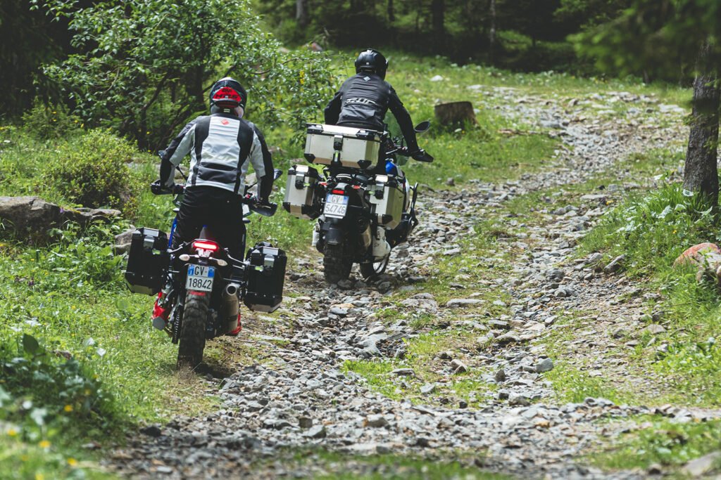 An adventure motorcycle equipped with GIVI Trekker Outback EVO panniers parked on a scenic, unpaved mountain road.