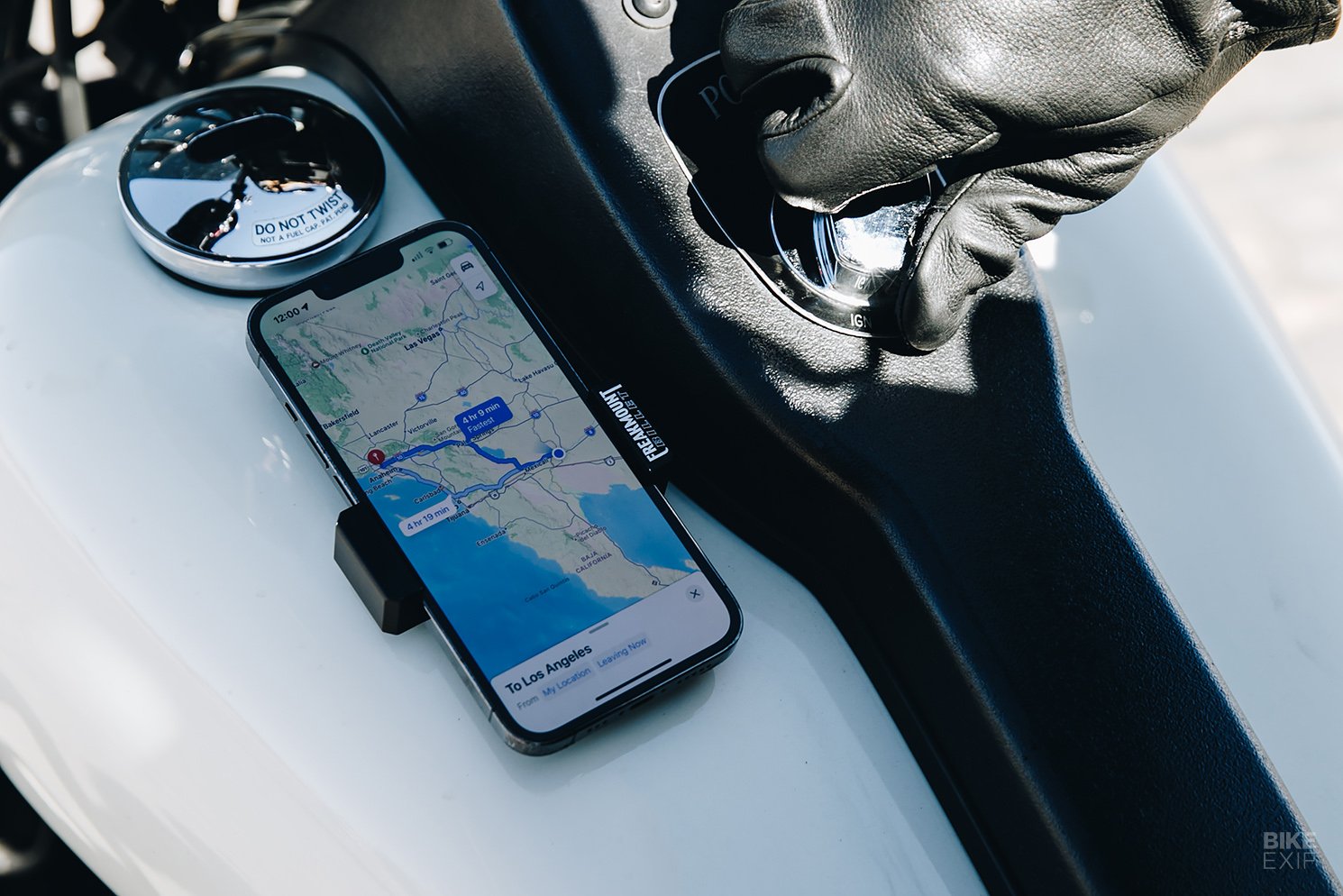 The Freakmount Billet phone mount, in black billet aluminum, shown magnetically attached to the steel fuel tank of a cruiser motorcycle.